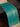 A close-up of a turquoise blue fabric banner or scroll with gold metallic script and a beige border, draped over a dark wooden surface.