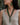 A close-up lifestyle shot of a woman wearing a bohemian green beaded necklace and matching drop earrings, set against a natural outdoor background with a tree trunk.
