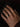 A close-up of a person's hand resting on a dark surface, wearing a simple metallic band ring on the ring finger.