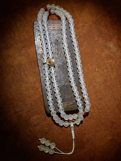 String of prayer beads with a small electronic device on a brown surface