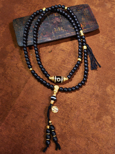 Black beaded necklace with gold accents on a brown surface