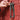 Hand holding a green beaded necklace against a red textured background