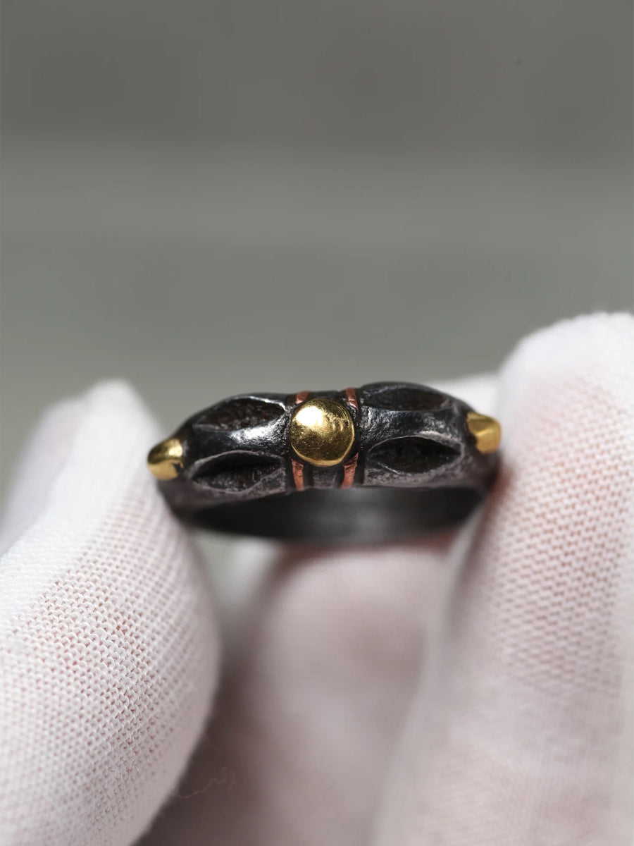 Close-up of a black ring with gold accents on a white background