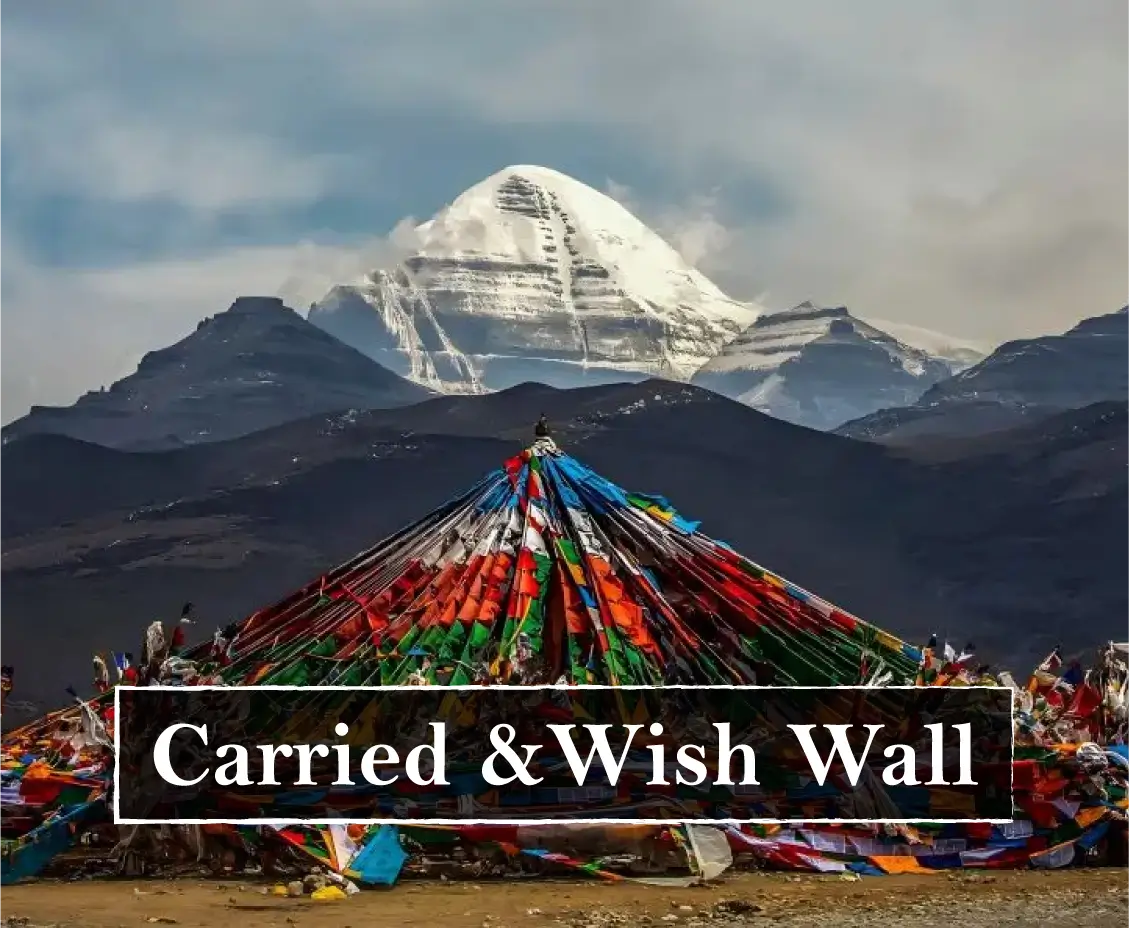A scenic landscape photo featuring a snow-capped mountain peak in the background and a large conical structure covered in multicolored prayer flags in the foreground. A white text banner overlay reads 'Carried & Wish Wall'.
