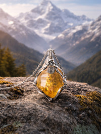 Amber pendant on a chain against a mountainous landscape