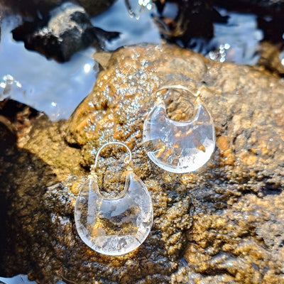 Clear glass earrings on a rock with water droplets