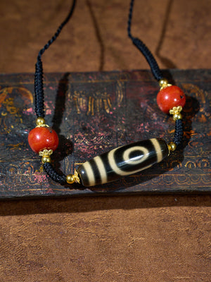 Necklace with red beads and a black and white bead on an old book