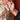 Hand holding a necklace with intricate design against a colorful fabric background