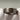 A close-up of a textured silver ring with gold engraved swirl patterns, held by white gloved hands against a soft gray background.