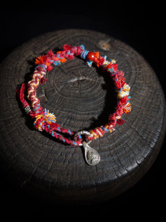 Colorful beaded bracelet with a silver charm on a dark surface