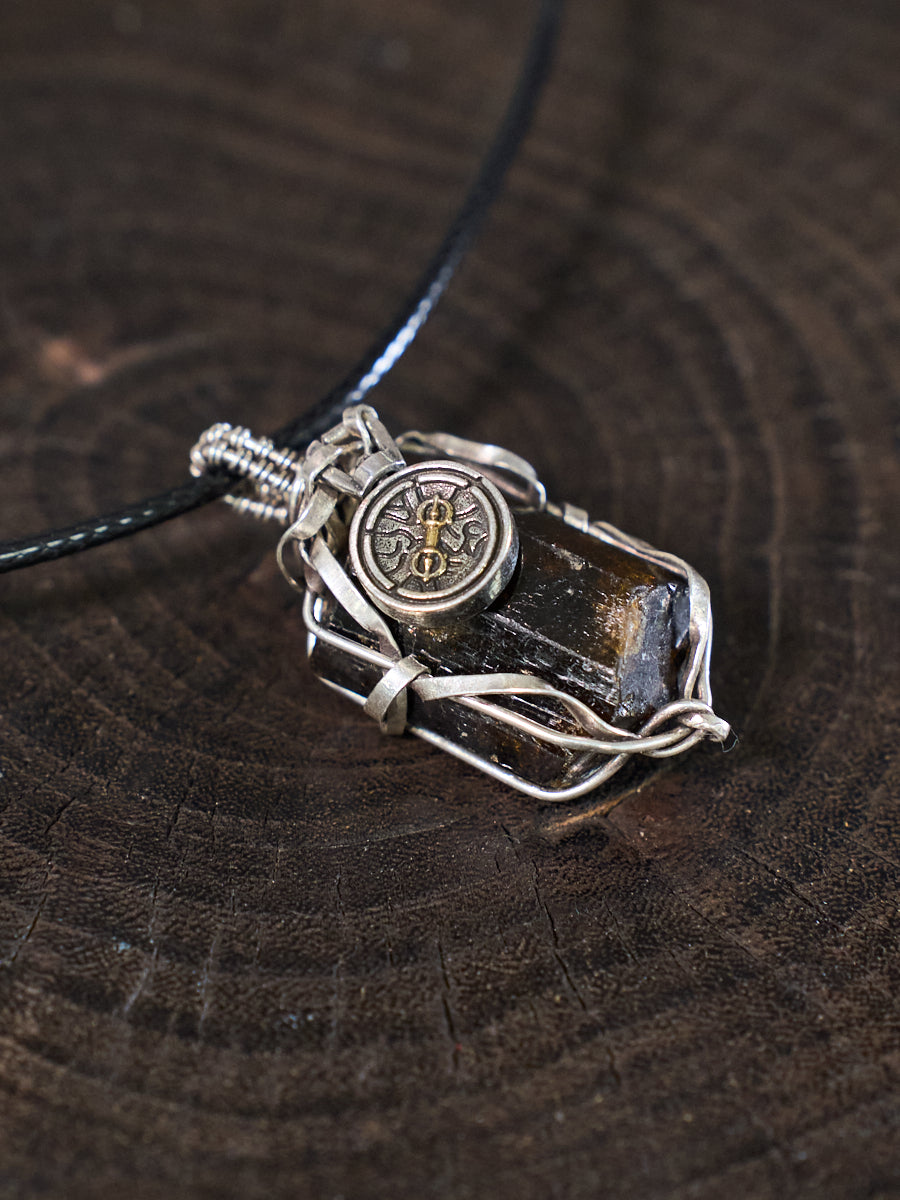 Silver pendant with a compass design on a dark wooden surface