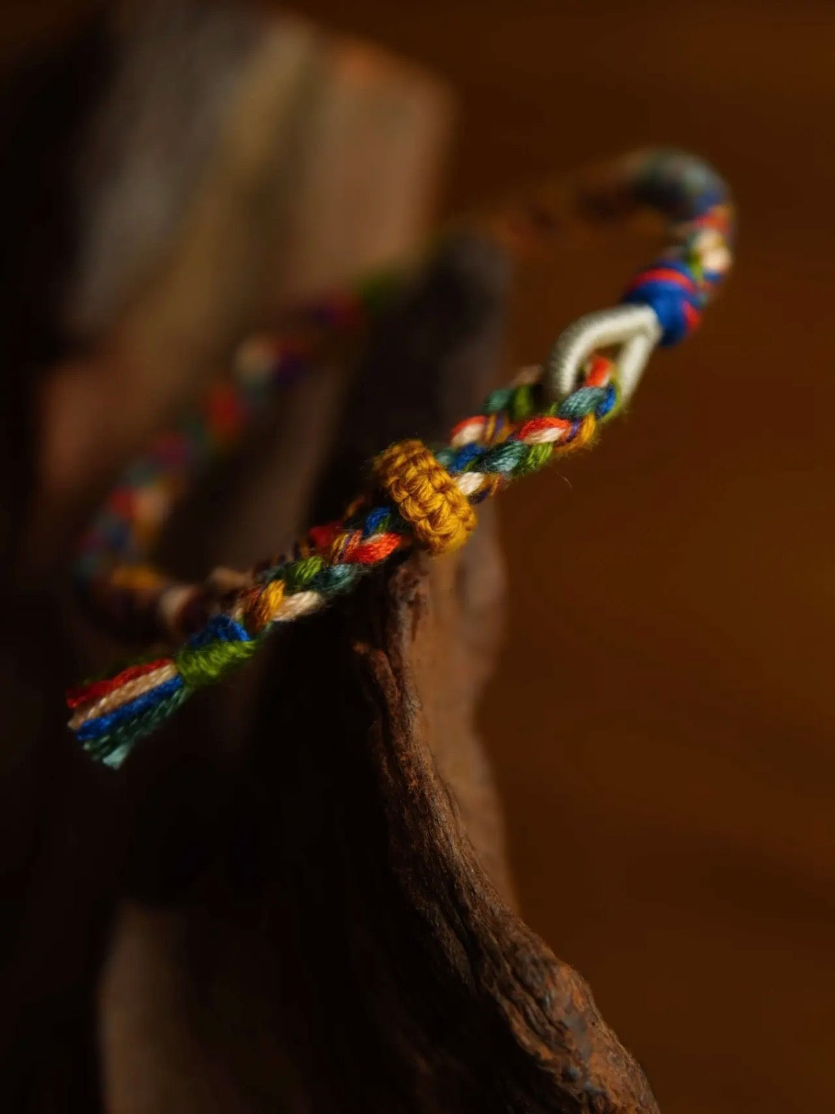 Colorful braided bracelet on a wooden surface with a blurred background