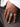 A close-up of a hand wearing a large silver-toned ring with a square turquoise inlay, resting on dark gray fabric next to a white fringed sleeve.