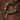 A handmade bohemian-style beaded bracelet with a carved wooden pendant, resting on a textured dark brown surface.