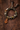 A handmade bohemian-style beaded bracelet with a carved wooden pendant, resting on a textured dark brown surface.