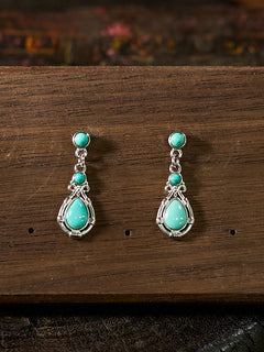 Turquoise teardrop earrings on a wooden surface