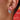 Close-up of an ear wearing a colorful hoop earring with a blurred background