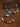 A beaded necklace and matching bracelet displayed on a textured brown surface with decorative script cards. The jewelry features dark red, turquoise blue, cream, and metallic silver beads, with a small heart-shaped silver charm engraved with Tibetan script.