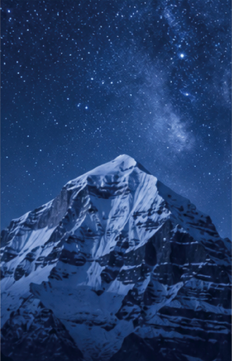 A snow-covered mountain peak under a deep blue star-filled night sky with the Milky Way visible above.