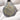 A teardrop-shaped metallic pendant with a textured silver-gray finish and an intricate gold mandala design, resting on a white knit fabric background.