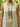 Person wearing a beige sleeveless top with a long, intricate necklace in a natural setting.
