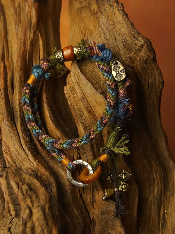 Multicolored braided bracelet with metal charms on a wooden surface