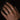A close-up of a person's hand resting on a dark surface, wearing a simple metallic band ring on the ring finger.
