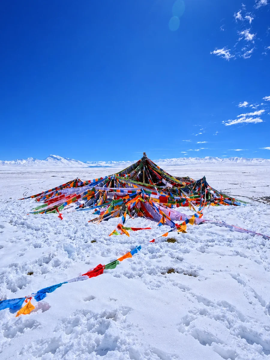 Tibetan prayer flags surrounded by snow and distant mountains