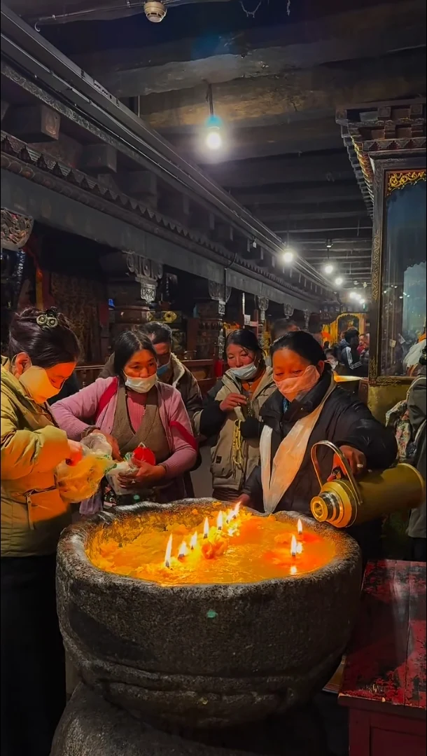 Devotees making a butter lamp offering inside a Tibetan temple